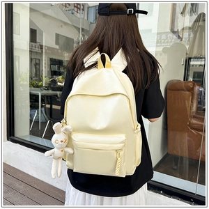 Close-up of a beige nylon backpack with cute bunny charm on a lifestyle model