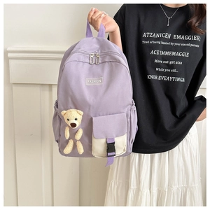 Detailed view of lavender school backpack featuring plush bear and fashion patch decoration