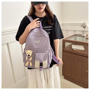 Detail of light purple nylon backpack featuring a 3D plush bear and fashion patch