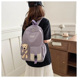 Detail view of lavender school backpack featuring contrast pocket and plush bear pendant