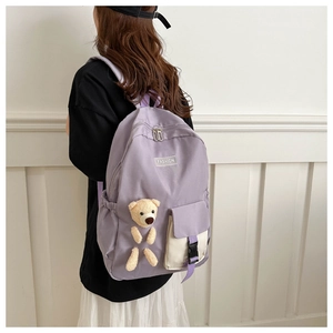 Detail of purple nylon backpack with teddy bear pendant and fashion logo on model