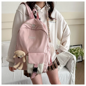Pink school backpack detail showing front buckle pocket and plush bear pendant accessory