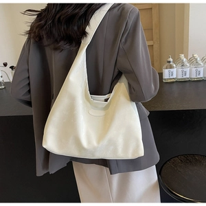 Gros plan sur un grand sac cabas en cuir crème à texture souple et détail ovale