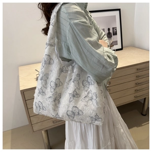 Lifestyle shot of white butterfly jacquard tote bag worn on shoulder by model