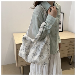 Detailed texture of a white canvas tote bag with grey butterfly prints and fringe edges