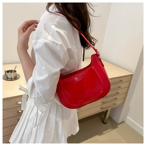 Glossy red hobo bag shoulder strap detail on a white striped shirt background