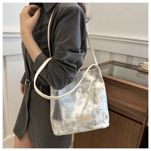 Detail of white tote bag with elegant blue butterfly embroidery and leather strap