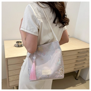 Detailed embroidery on purple satin bucket bag with long pink tassel and side leather label