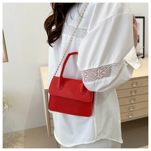 Détail du sac à main en cuir grainé rouge avec chaîne dorée et poignée supérieure