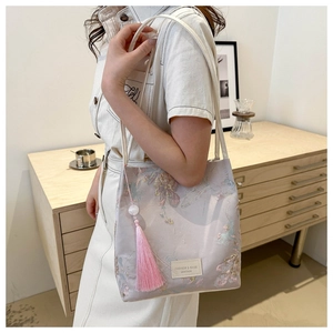 Detailed macro view of pink floral jacquard fabric and delicate tassel on shoulder bag