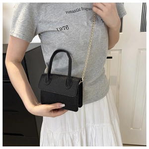 Mini sac bandoulière noir en cuir grainé avec chaîne dorée porté par un mannequin