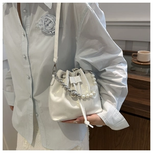 Détail du sac seau blanc à cordon avec poignée décorative en perles et perles argentées
