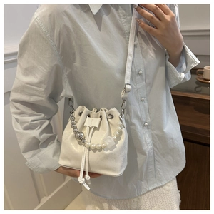 Vue détaillée du sac seau blanc avec poignée en perles et fermeture à cordon