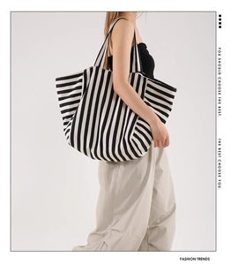 Detail of a large black and white striped canvas tote bag shown from a side profile view