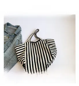 Detailed close-up of a striped canvas tote bag with a denim jacket on white background