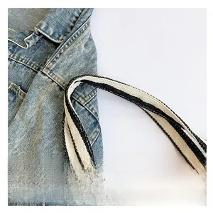 Detail of black and white striped woven tote bag strap showing thick texture on denim outfit