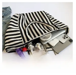 Top view showing a spacious striped canvas tote bag with a laptop and daily essentials