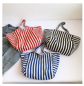 Detail of striped canvas tote bags in red, black, and blue patterns on white background