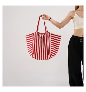 Detail of red and white striped tote bag showing large capacity and canvas texture on model