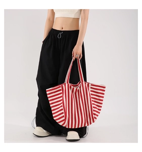 Close-up of a large capacity red and white striped canvas tote bag held by a model