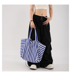 Vertical blue and white striped canvas tote bag shown on model for daily commuting