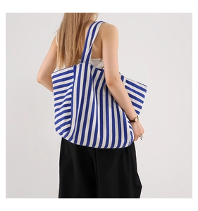 Rear view of a large blue and white striped canvas tote bag worn over the shoulder