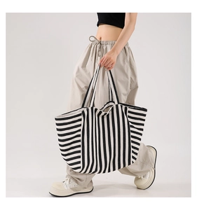 Detail of a large striped canvas tote bag showing the textured fabric and casual fit