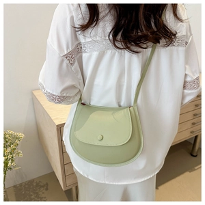 Close-up of light green saddle bag with glossy finish on a minimalist interior background