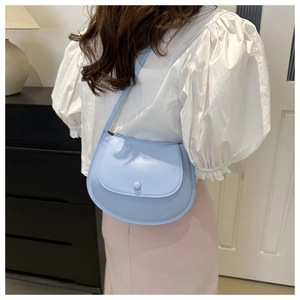 Light blue faux leather saddle bag with chain strap shown on model for size and fit