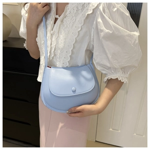 Detail view of light blue saddle bag styled with white lace shirt and pink skirt