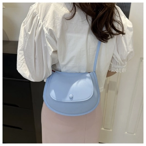 Back view of a model wearing a light blue leather saddle bag with chain strap