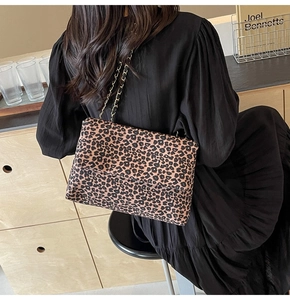 Détail du sac en toile léopard avec bandoulière en chaîne dorée porté par un mannequin