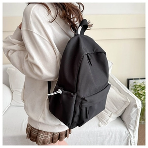 Detail view of black nylon backpack side pocket with drawstring and sleek texture