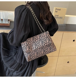 Detail of leopard print canvas bag with woven gold chain strap and flap closure