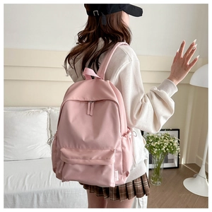 Rear view of a stylish pink backpack with drawstrings and fashion label on a model