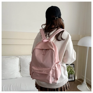 Side view of pink fashion backpack featuring side drawstring pocket and woven label