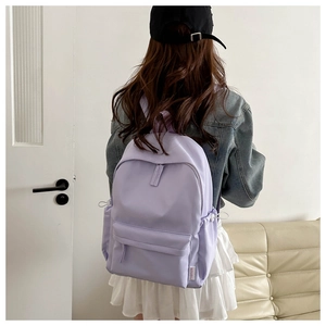 Detail of light purple oxford cloth backpack showing side drawstring pockets and logo label