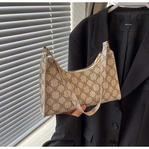 Dettaglio della borsa a mezzaluna con motivo a trifoglio su uno sfondo di blazer nero
