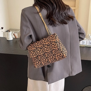 Sac à bandoulière en toile léopard chic avec chaîne dorée porté sur un blazer gris