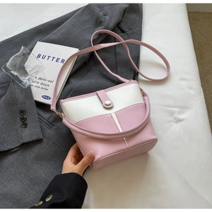Dettaglio borsa a secchiello bicolore rosa e beige con manico e cuciture su lenzuola