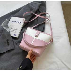 Dettaglio della borsa a secchiello rosa e bianca con tracolla regolabile e manico
