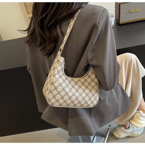 Close-up of a retro crescent hobo shoulder bag with geometric patterns on a female model
