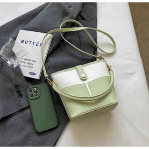 Dettaglio della borsa a secchiello verde chiaro con fibbia bianca e tracolla minimalista