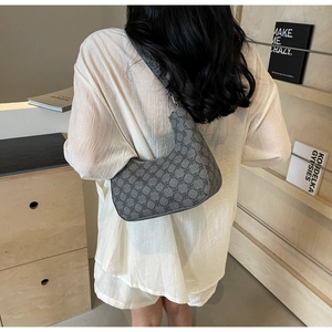 Model wearing a grey vintage crescent bag with floral pattern in a minimalist setting