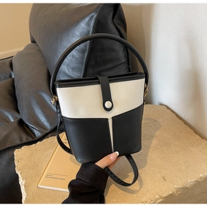Dettaglio della borsa a secchiello bicolore con patchwork a V e manico in pelle