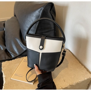 Dettaglio della borsa a secchiello bicolore nero e bianco su una pietra minimalista
