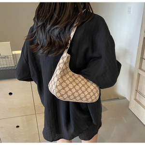 Detail of crescent shoulder bag with vintage monogram pattern worn by a model