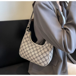 Detail of vintage hobo bag with four-leaf clover print worn with a grey blazer