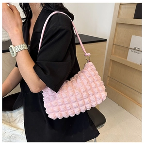 Sac à bandoulière rose avec texture à bulles porté sur un blazer noir chic et moderne