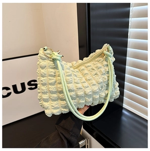 Detail of light green bubble pleated fabric and metal ring strap attachment on bag